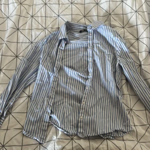 Blå och vit randig skjorta från Zara - Säljer en stilren blå och vit randig skjorta från Zara. Skjortan har långa ärmar och knappar hela vägen ner. Perfekt för både vardag och fest! 🌀
