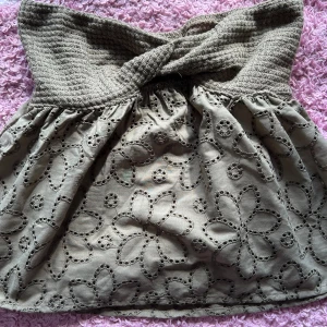 Beige axelbandslös topp med blommönster - Säljer en superfin grön axelbandslös topp med ett vackert blommönster. Toppen har en smockad överdel som ger en bra passform och en luftig nederdel. Perfekt för sommardagar eller en avslappnad festkväll!