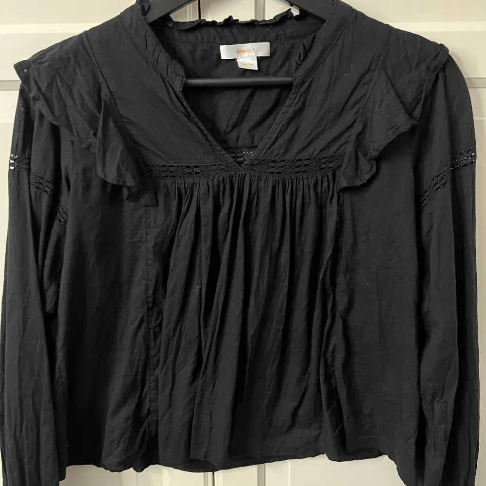 Svart blus från Gina Young. Söta detaljer med volang. Perfekt till fest eller till vardags. Använd fåtal gånger då den var för kort för mig! Storlek 158/164. Puserot.