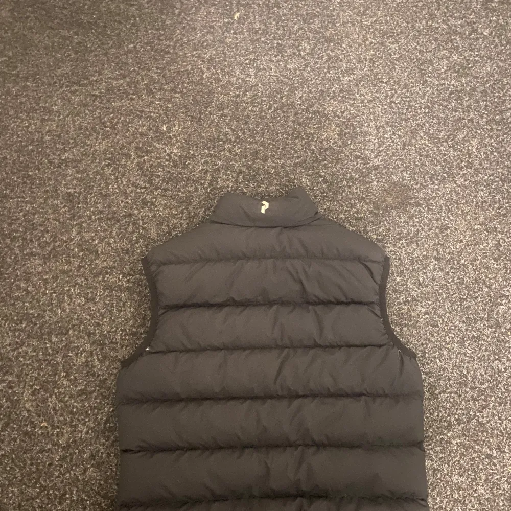 Säljer en svart dunväst från Peak Performance med dragkedja framtill. Västen är perfekt för våren och sommaren . Takit.