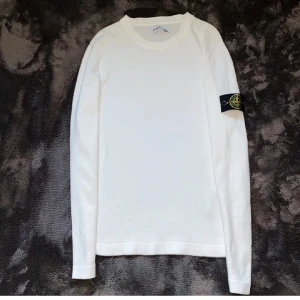 Vit långärmad tröja från Stone Island - Säljer en stilren vit långärmad tröja från Stone Island med det ikoniska märket på ärmen. Tröjan är i storlek S och köptes in för 3500kr. Skick 8/10, enda defekten är det lilla hålet (bild 4) och därav säljs tröjan för det låga priset. Väldigt lätt att fixa för den som vill det. 😃