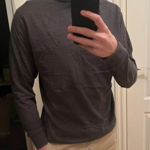 Mörkgrå polotröja från Clique (2 för 1) - Säljer en stilren mörkgrå polotröja från Clique i storlek S. Tröjan har långa ärmar och en klassisk polokrage, perfekt för kyligare dagar. Den är tillverkad i ett mjukt och bekvämt material. Har 2 likadana, så man får båda på köpet