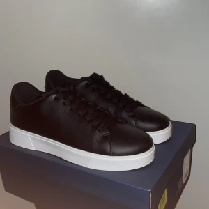 Vagabond skor  - Snygga svarta sneakers i skinn med vit sula. De har en klassisk design med snörning och en bekväm passform. Perfekta för en stilren look.