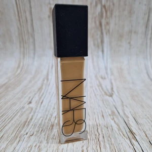 Natural Radiant Longwear Foundation från NARS - Natural Radiant Longwear Foundation i nyansen Punjab från NARS. Denna foundation ger en naturlig och strålande finish med lång hållbarhet. Förpackningen är elegant med en fyrkantig glasflaska och svart lock.