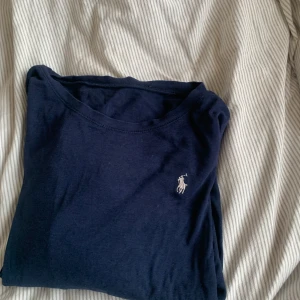 Mörkblå tröja från Ralph Lauren - Säljer en klassisk mörkblå tröja från Ralph Lauren med det ikoniska vita logotypbroderiet på bröstet. Perfekt för en stilren look.