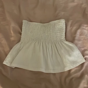 Vit tubtopp från Gina Tricot - Säljer en söt vit tubtopp från Gina Tricot. Toppen har en smockad överdel och en lätt utsvängd nederdel som ger en fin siluett. Perfekt för varma sommardagar!🌟