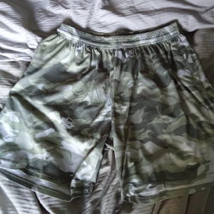 Camouflage shorts från Gorilla Wear - Säljer ett par coola camouflage shorts från Gorilla Wear. De har en elastisk midja och praktiska dragkedjefickor. Perfekta för en aktiv livsstil!