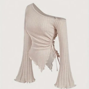 Beige oneshoulder topp - Trendig beige oneshoulder topp med ribbad struktur och långa ärmar. Toppen har en snygg knytdetalj i sidan och en asymmetrisk nederkant som ger en unik look.