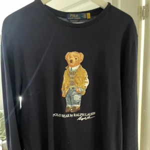 Svart långärmad t shirt  från Ralph Lauren - Säljer en svart långärmad t shirt från Ralph Lauren med en ikonisk Polo Bear-tryck på framsidan. Perfekt för en avslappnad och stilren look.