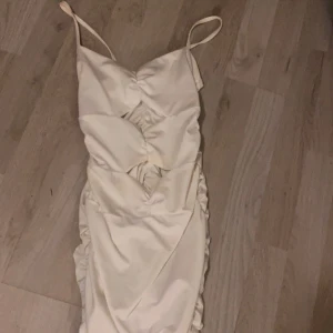 Vit axelbandslös klänning - Elegant vit klänning med smala axelband och rynkade detaljer framtill. Perfekt för en somrig look med sin lätta och luftiga design.