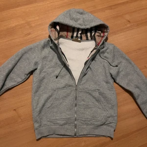 Grå Burberry hoodie - Säljer en grå Burberry hoodie använd ett fåtal gånger. Storlek L men passar som M. Priset är inte hugget i sten 