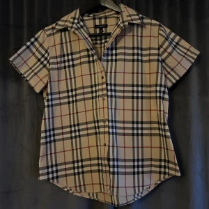 Rutig kortärmad skjorta från Burberry - Säljer en klassisk rutig skjorta från Burberry i beige. Skjortan är i mycket vackert skick då de inte blivit så använd. Kontakta gärna vid frågor☺️