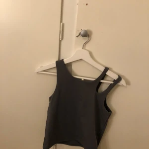 Grå linnetopp från H&M Move - Snygg grå linnetopp från H&M Move. Perfekt för träning eller en avslappnad dag. Toppen har en enkel design med breda axelband och är tillverkad i ett bekvämt material.