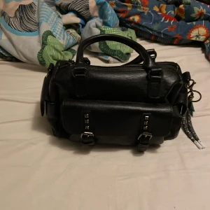 Svart handväska med dragkedja - En fin liten svart väska med ett band tillbehör. Som inte kommer till användning, jag har bara använt den två gånger men den ser helt ny ut. Kontant mig gärna  om du har flera frågor🩷