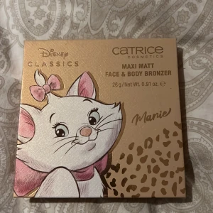 Maxi Matt Face & Body Bronzer från Catrice - Catrice Disney Classics Maxi Matt Face & Body Bronzer i nyansen 'Ladylike'. Bronzer med motiv av Marie från Aristocats. Förpackningen har en spegel och bronzern har ett leopardmönster. Denna produkt är inprincip oanvänd har svept över en borste för att testa men detta var inget för mig därav säljer jag denna jättesöta palett