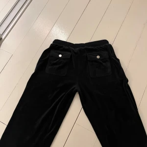 Svarta mjukisbyxor med fickor - Säljer ett par svarta mjukisbyxor i mjukt material med praktiska fickor framtill. Byxorna har en bekväm passform och dragsko i midjan för justerbarhet. Perfekta för en avslappnad stil.