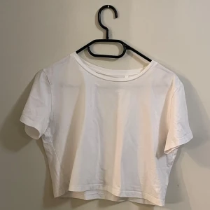 Vit croppad t-shirt från Lager 157 - Säljer en enkel och stilren vit croppad t-shirt från Lager 157. Perfekt för en avslappnad look. T-shirten har korta ärmar och en rund halsringning.