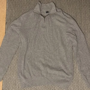 Half Zip tröja  - Säljer en stilren grå ribbad tröja med dragkedja i halsen. Perfekt för kyligare dagar och enkel att matcha med olika outfits.