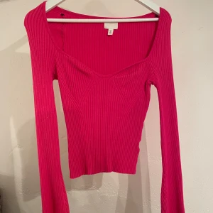 Rosa ribbad topp från H&M - Snygg rosa ribbad topp från H&M med djup v-ringning och långa ärmar. Använd och smått nopprig men annars fint skick! 