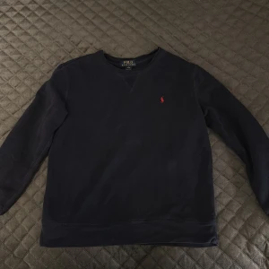 Mörkblå sweatshirt från Ralph Lauren - Säljer en stilren mörkblå tröja från Polo Ralph Lauren med det klassiska röda logotypbroderiet på bröstet. Tröjan har långa ärmar och en bekväm passform. Perfekt för en avslappnad look. Pris kan diskuteras. Tvättad och stryks innan jag skickar