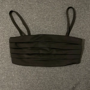 Svart tubtopp med dragkedja - Snygg svart tubtopp med smala axelband och dragkedja i ryggen. Perfekt för en stilren look.