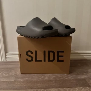 Yeezy slides - Säljer ett par grå Adidas slides med en stilren design och räfflad sula för extra grepp. Perfekta för avslappnade dagar.