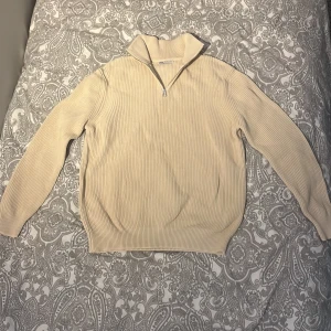 Beige ribbad tröja från Zara - Säljer en stilren beige ribbad tröja från Zara med dragkedja vid halsen. Perfekt för lager-på-lager och passar till många olika outfits.