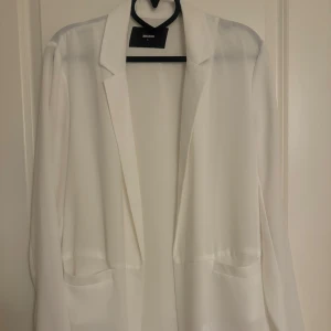 Vit kavaj från Bik Bok - Snygg och stilren vit kavaj från Bik Bok i storlek S. Perfekt för en chic och elegant look. Kavajen har en klassisk design med långa ärmar och en enkel krage.