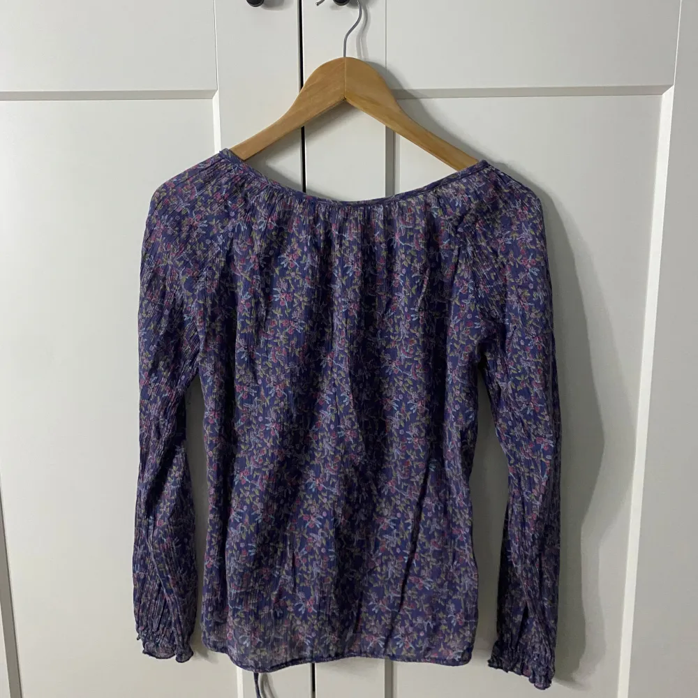 Detta är en fin blommig långärmad blus som passar perfekt inför sommaren! Den har snören så att man kan dra åt i midjan.. Puserot.