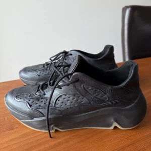 Svarta sneakers från Ecco - Snygga svarta sneakers från Ecco i skinn med snörning. De har en robust sula och stilren design, perfekt för en modern look. Knappt använda.