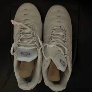 Vita Nike tns - Snygga vita Nike sneakers med snörning och synlig luftdämpning i sulan. Perfekta för en sportig look med en stilren design. Aldrig använda