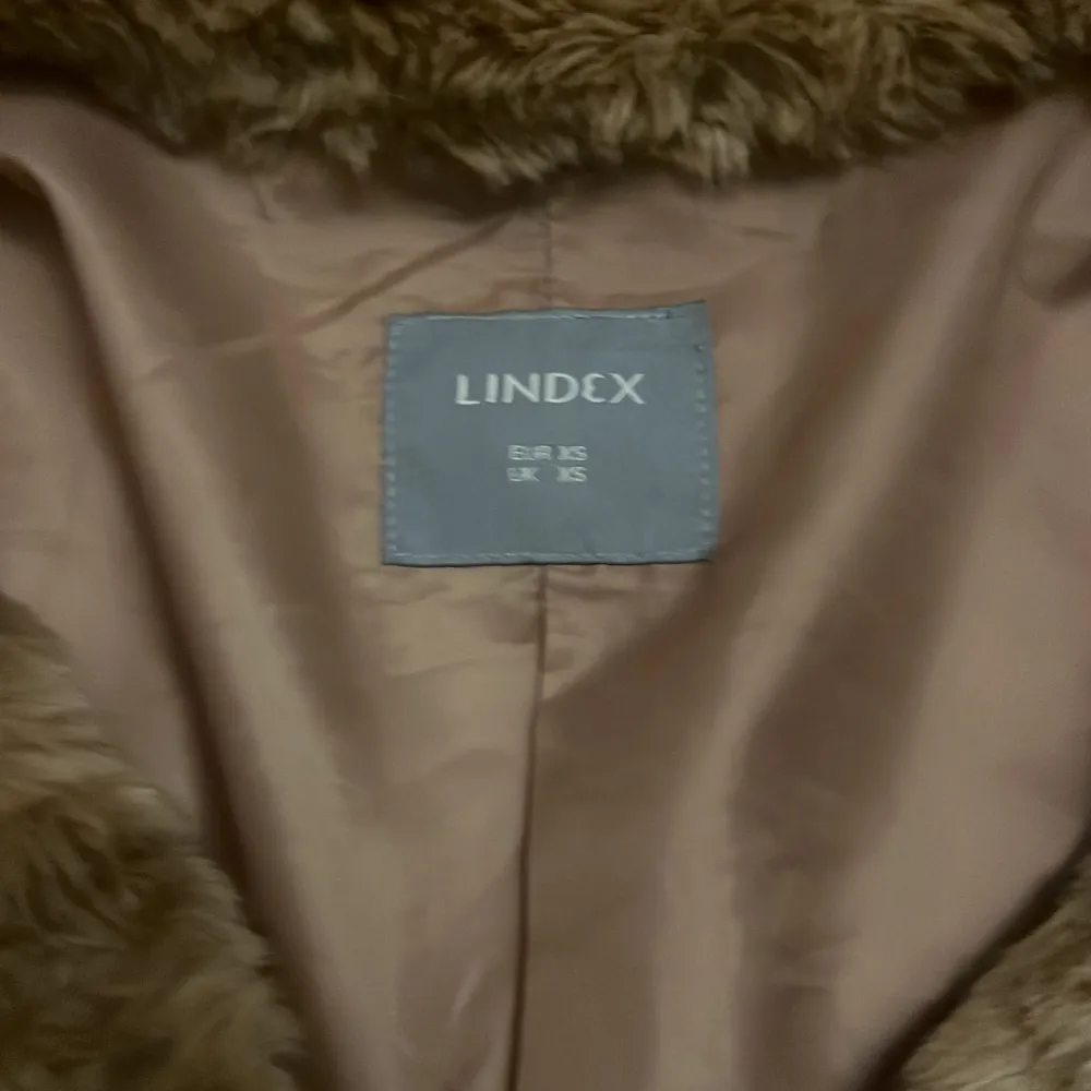 Säljer en mysig brun pälsjacka från Lindex i storlek XS. Jackan har en mjuk och fluffig yta med långa ärmar och knäppning framtill. Perfekt för att hålla sig varm och stilren under kyliga dagar.. Takit.
