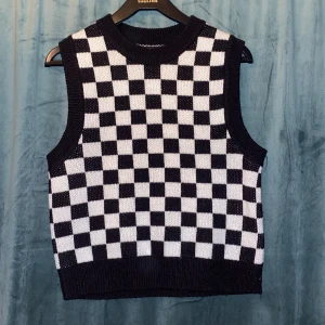 Svartvit rutig väst från FB Sister - Snygg svartvit rutig väst från FB Sister i storlek S. Perfekt för att lägga till en trendig touch till din outfit. Västen har ett klassiskt rutmönster och är ärmlös med ribbade kanter.