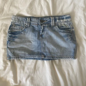 Lågmidjad minikjol denim - Säljer då den inte passar mig. Den har coola slitningar på bak-och framfickor samt nitar. Den är i gott skick.  Mått: Midja rakt över- 37 cm Längd- 27 cm  Köp nu är på!