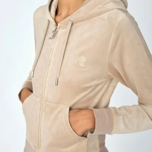 Juicy Couture Classic velour zip hoodie - Juicy Couture Classic velour zip hoodie i beige. Storlek XL men liten i storleken (som juicy alltid är i tröjor) så passar mer som en M-L.  Har bara använts ca 3 gånger. Köpt på raglady. Kan frakta men även mötas upp i Kungsbacka.