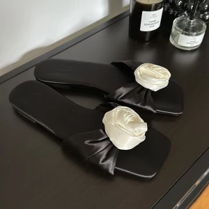 Sandaler med blomma - Säljer dessa fina svarta satin sandaler med gullig vit blomma på. Aldrig använda. Perfekt under sommaren eller på semestern🌸 skriv vid funderingar!