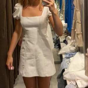 Vit klänning zara - En jättesnygg vit klänning från zara med snörning i ryggen. Säljer pga kommer inte till användning. 