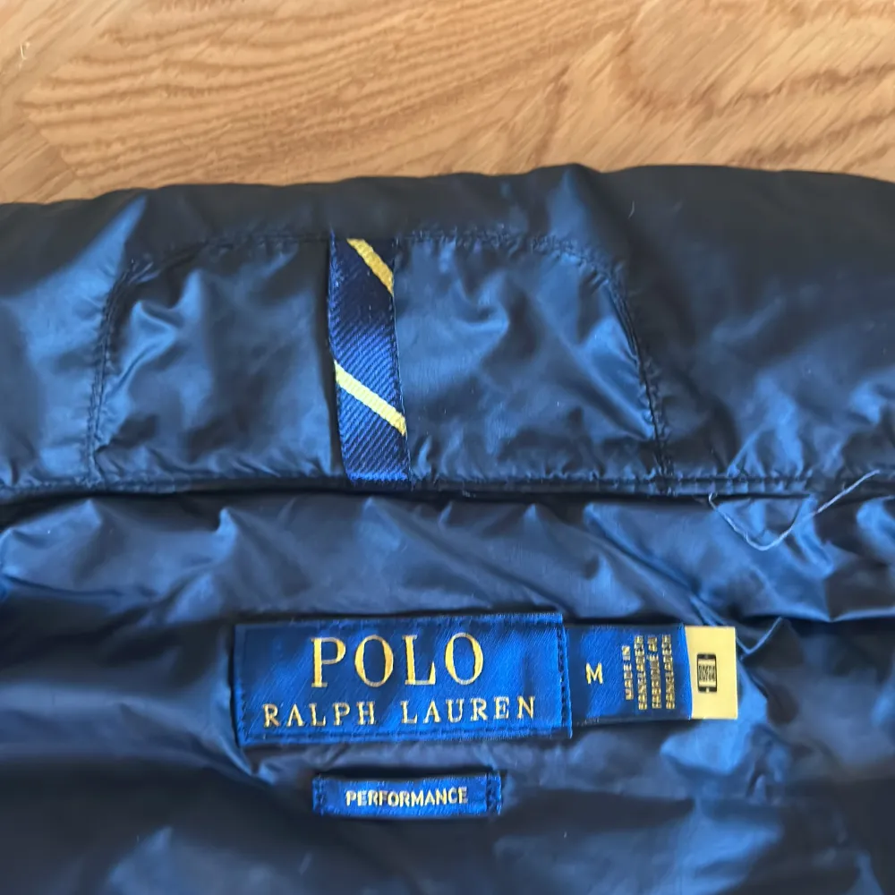 Säljer en snygg svart dunväst från Polo Ralph Lauren. Västen har en quiltad design och är perfekt för höst och vår. Den har en dragkedja framtill och två praktiska fickor med dragkedjor. Västen är i nyskick. Köpt på NK så kvitto finns.. Jackor.