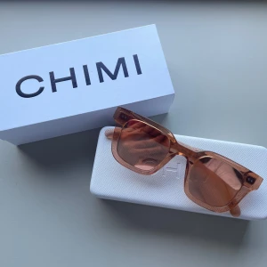 Bruna solglasögon från CHIMI - Säljer ett par snygga brun/ orangea solglasögon från CHIMI. Medföljer med ett stilrent vitt fodral. Använda men i väldigt fint skick. 