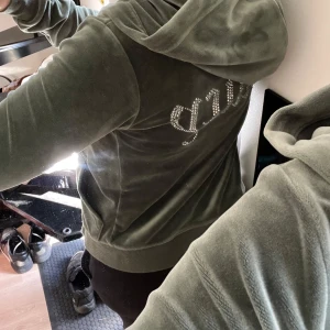 Juicy couture  - Fin tröja i khaki grön från juicy couture. Fint skick, dock har metalldetaljerna på snörena lossnat samt några få stenar på dragkedjan.