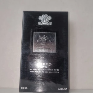 Creed Aventus Eau de Parfum 100ml - Säljer en lyxig flaska Creed Aventus Eau de Parfum, 100ml. Förpackningen är elegant och svart med silverdetaljer och har en klassisk och exklusiv känsla. Perfekt för den som vill ha en sofistikerad och tidlös doft.