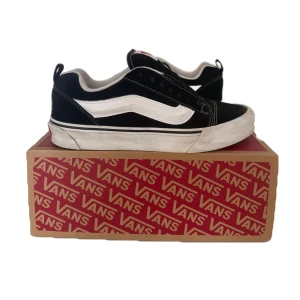 Vans knu skool  - Säljer ett par svarta Vans sneakers i storlek 42 för herrar. Skorna är i bra skick med vit sula och vita snören. De har den klassiska Vans-loggan på sidan och är perfekta för vardagsbruk. Kommer med originalkartong. 