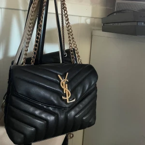 Saint Laurent väska - Säljer nu min ganska så välanvända saint Laurent väska tappat lite färg på själva märket sen kedjorna men inget man tänker på så mycket, jätte stor och får plats med mer än vad man tror. Ablout inte säker på ifall den är äkta eftersom den tappat färg