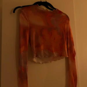 Färgglad croppad topp från NLY One - En meshtopp från Nelly i storlek S som går i rosa/orangea toner. Använd 1 gång! 