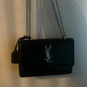 Ysl väska  - Säljer denna fina svart Ysl väska. Den är i god skick, dock vara lite sliten i insidan. Färgen har försvunnit jättelite på metall banden men inget som syns från långt håll alls.  OBS väskan är FEJK