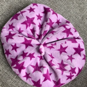 Lilla mössa med lilla stjärnor  - Storlek 8-11 lilla mössa med stjärnor med en liten knop på