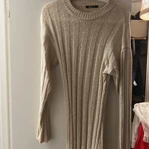Beige ribbad långklänning från Gina Tricot - Snygg beige långklänning från Gina Tricot i ribbat material. Klänningen har långa ärmar och en rund halsringning, perfekt för en stilren look.