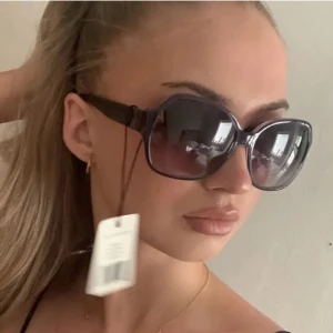 Svarta solglasögon från Kabi - Snygga svarta solglasögon från Karl Lagerfeldt med en elegant och modern design. De har en bred båge och mörka glas som ger ett stilrent intryck. Perfekta för soliga dagar!