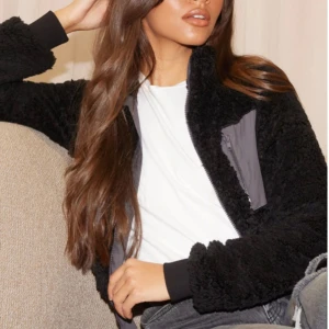 Svart teddyjacka med dragkedja och ficka framtill. - Aldrig använd svart teddy kofta med dragkedja och ficka framtill. Koftan har långa ärmar och en hög krage för extra värme.