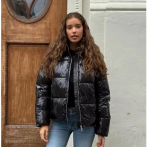 Svart glansig pufferjacka - Snygg svart glansig pufferjacka med dragkedja. Perfekt för kyliga dagar med sin quiltade design som håller värmen. Jackan har en normal passform och långa ärmar.